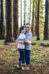 Bruder und Schwester umarmen sich im Wald. - CAVF79362