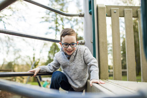Kleiner Junge klettert auf Spielplatzgeräten., lizenzfreies Stockfoto