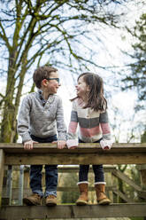 Best friends look at each other while climbing on railing. - CAVF79372