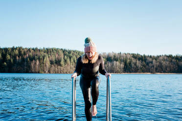 Frau schreit beim Schwimmen im kalten Wasser im Meer im Winter - CAVF79405