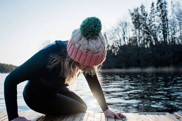 Woman climbing out of the water from cold water ice swimming in Sweden - CAVF79406