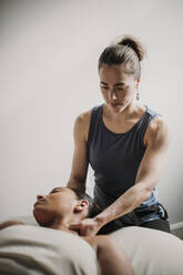 Female massage therapist treats her african american patient - CAVF79430