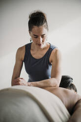 Massagetherapeutin behandelt Patientin drinnen auf Massagetisch - CAVF79438