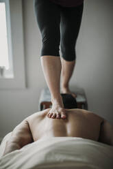 Massagetherapeutin arbeitet mit Ashiatsu-Technik am Rücken des Patienten - CAVF79444