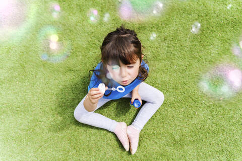 Porträt eines kleinen Mädchens, das Seifenblasen bläst, lizenzfreies Stockfoto