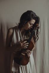 Frau hält Geige mit geschlossenen Augen - GMLF00114