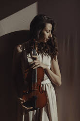 Frau hält Geige mit geschlossenen Augen - GMLF00115