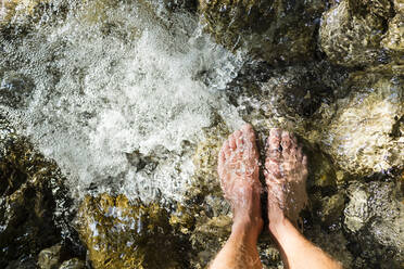 Man's feet standing on stone in a brook - WFF00348