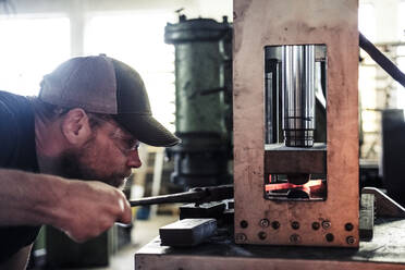 Messermacher bei der Arbeit mit Damaststahl am hydraulischen Schmiedehammer - WFF00349