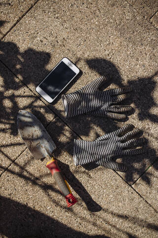 Smartphone next to hand trowel and gardening gloves stock photo