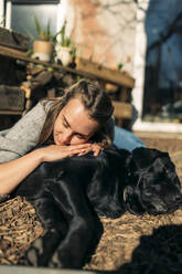 Entspannte junge Frau mit Hund im Garten - GUSF03562