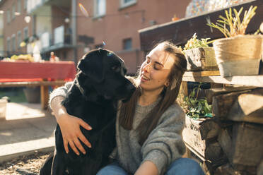 Glückliche junge Frau mit Hund im Garten - GUSF03565