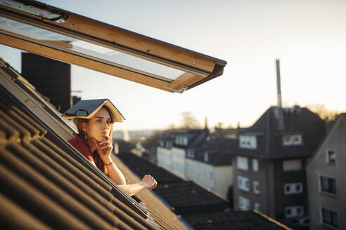 Junge Frau mit einem Buch auf dem Kopf am Fenster - GUSF03566