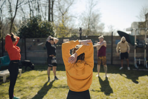 Gruppe von Freunden beim gemeinsamen Training im Garten, lizenzfreies Stockfoto