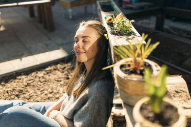 Young woman enjoying the sunshine in garden - GUSF03603