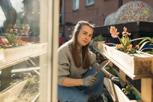 Porträt einer jungen Frau bei der Arbeit im Garten bei Sonnenschein - GUSF03604