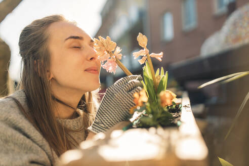 Junge Frau riecht an einer Blume im Garten - GUSF03607