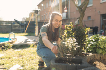 Junge Frau arbeitet im Garten bei Sonnenschein - GUSF03614