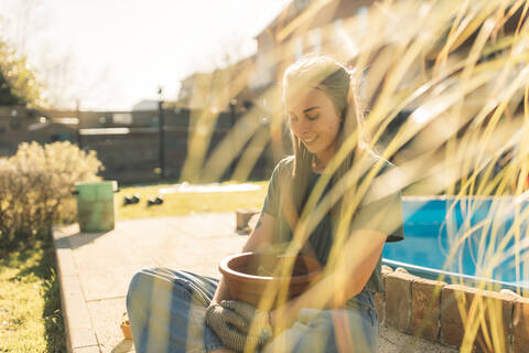 Young woman in garden with seedling in flowerpot stock photo