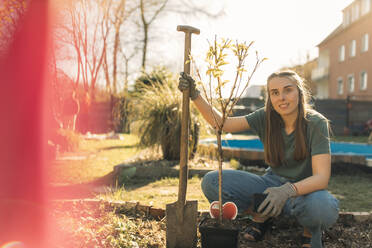 Porträt einer jungen Frau im Garten mit Spaten - GUSF03630