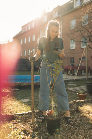 Young woman using smartphone in garden stock photo