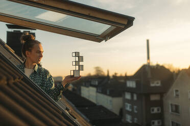 Junge Frau hält Design am Fenster am Abend - GUSF03656