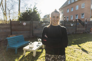 Porträt einer jungen Frau, die im Garten im Sonnenschein steht - GUSF03660