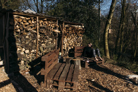 Young woman sitting on pallet at fireplace stock photo