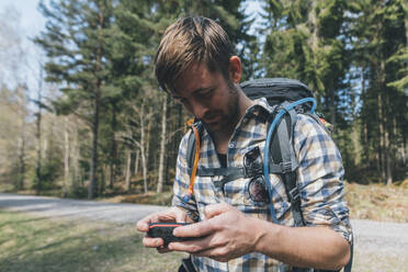 Young man checking navigation device in forest - GUSF03688