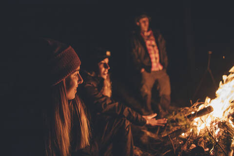 Freunde wärmen sich am Lagerfeuer auf, lizenzfreies Stockfoto