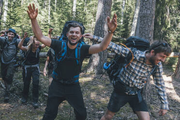 Junge Leute auf Rucksacktour in der Natur, lachend und in die Kamera winkend - GUSF03696