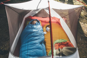 Junge Frau schläft im Schlafsack in einem Zelt - GUSF03701