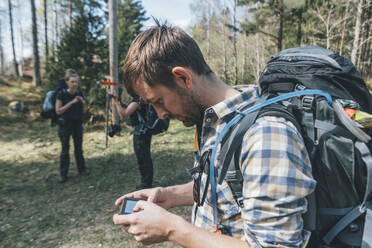 Young man checking navigation device in forest - GUSF03718