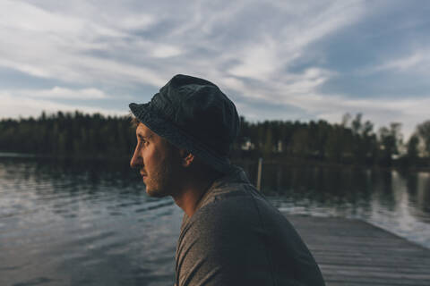Young man with hat, looking at lake stock photo