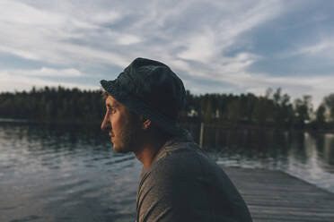 Junger Mann mit Hut, Blick auf den See - GUSF03746