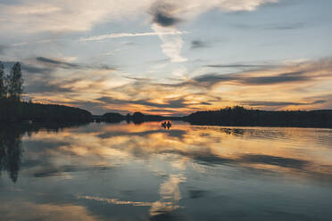 Junge Leute beim Bootfahren auf dem See bei Sonnenuntergang - GUSF03748