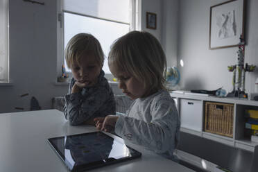 Kleines Mädchen testet digitales Tablet, während ihr älterer Bruder sie beobachtet - JOSEF00323