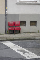 Two red old chairs standing side by side on pavement - JOSEF00327