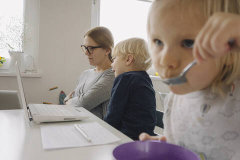 Mutter mit zwei Kindern während der Quarantäne zu Hause, lizenzfreies Stockfoto