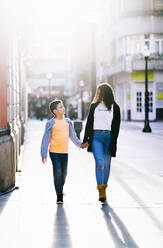 Mother and son walking hand in hand in the city - DGOF00909