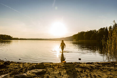 Junge spaziert im See gegen den Himmel bei Sonnenuntergang, Strausberg, Deutschland - OJF00387