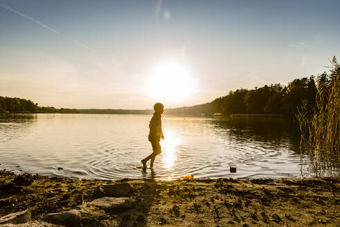 Junge geht bei Sonnenuntergang im See spazieren, Strausberg, Deutschland - OJF00388