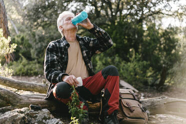 Wanderer mit Rucksack macht eine Pause und trinkt Wasser aus einer Flasche - AFVF06115