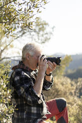 Älterer Mann beim Fotografieren in der Natur - AFVF06128