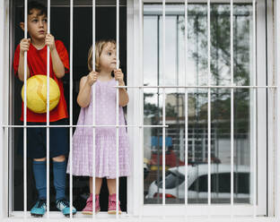 Children standing at open window at window grate - JRFF04367