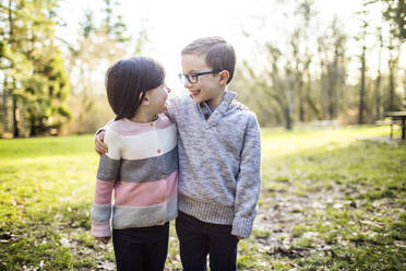 Cute brother and sister looking at each other outdoors. - CAVF79465