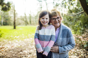 Grandma holds granddaughter in outdoor setting. - CAVF79483