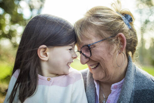 Großmutter lächelt ihre Enkelin im Freien an. - CAVF79484