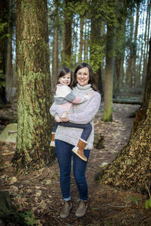 Mutter hält ihr süßes kleines Mädchen im Wald. - CAVF79496