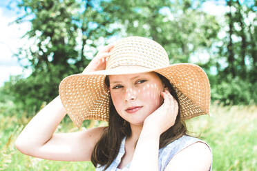 Girl in a Green Field Wearing a Floppy Sun Hat on a Bright Summer Day - CAVF79529